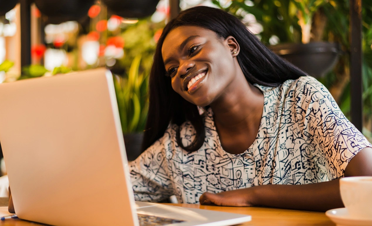 Smiling student studying online on a laptop in a café
